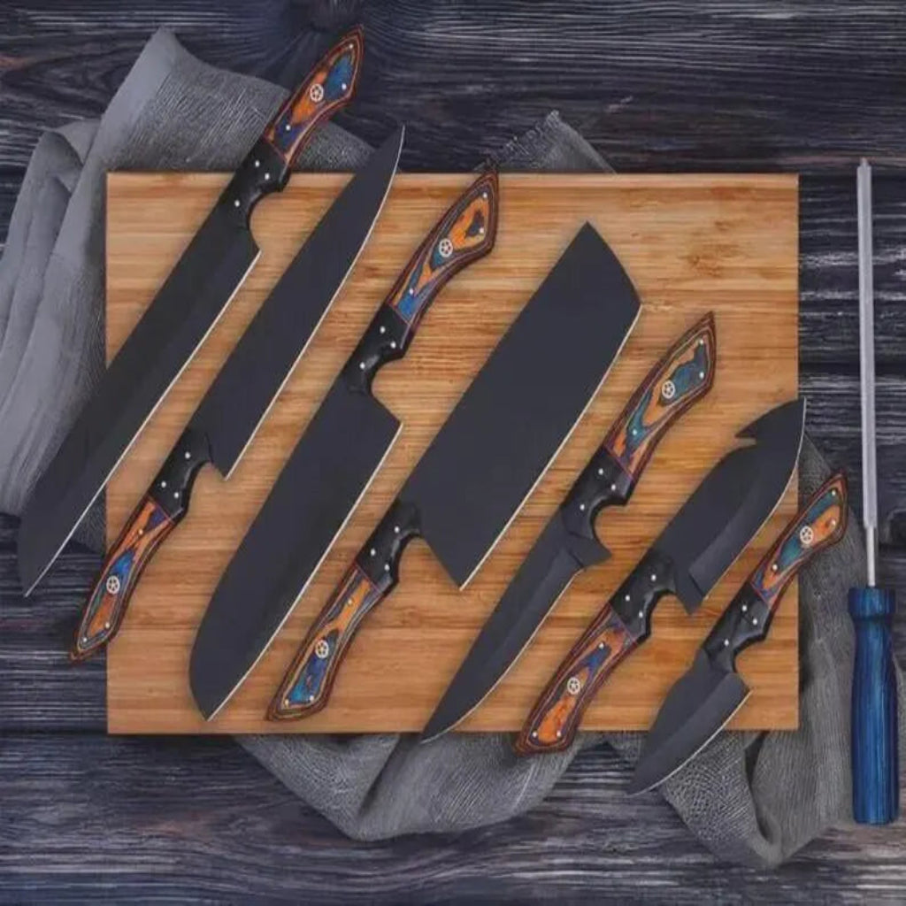 A set of six large fixed-blade knives with matte black blades and colorful wood-patterned handles, arranged diagonally on a wooden cutting board with a gray cloth and a honing steel on a dark wood surface.